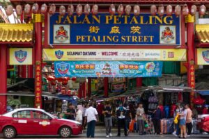 Vibrant scene of Petaling Street in Kuala Lumpur with market stalls and diverse crowd.